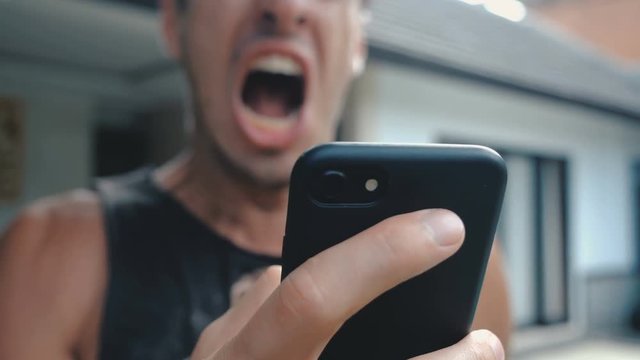 Angry Man Using Smartphone. Furious yelling man with smartphone in hand