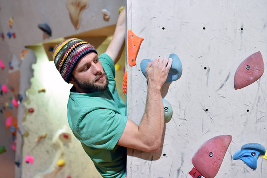climber bouldering in a sports hall - holding on to the handle of an artificial rock wall