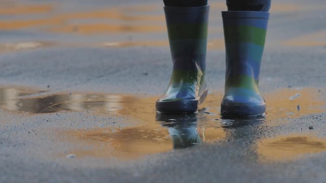 Detail of child rubber boots jumping on puddle, childhood  freedom