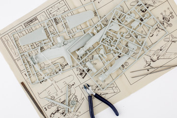 kit for assembling gray plastic airplane model on white bsckground
