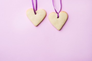 Fototapeta premium Homemade cookies in the shape of a heart on a pastel pink background. Copy space. Concept Valentine's Day