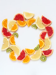Creative circle arrangement of sliced fruits - kiwi, orange and grapefruits. Flat lay with copy space