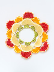 Creative pattern of sliced fruits - kiwi, orange and grapefruits - arranged in a circle. Flat lay with copy space