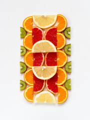 Fototapeta na wymiar Creative pattern of sliced fruits - kiwi, orange and grapefruits, flat lay style