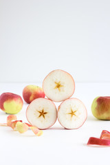 Stacked sliced pieces of apple and whole apples in the background