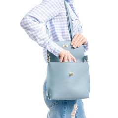 Woman in jeans and blue shirt put in blue bag macro on white background isolation