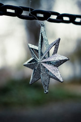 Decoración de navidad compuesta por una estrella de navidad en color plateado en una cadena en el...