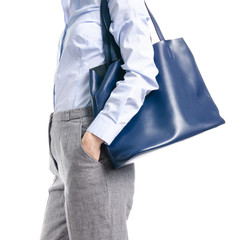 Woman in gray pants and blue shirt blue bag in hand macro on white background isolation