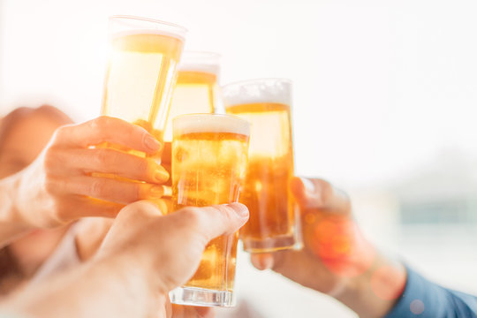 Group of happy friends drinking beer outdoors together - concept of friendship and celebration