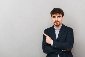 Business man isolated over grey wall background pointing.