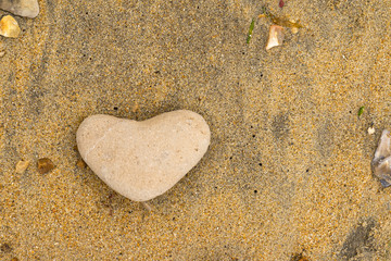 Close up of a yellow heartshaped pebble lying on a sandy beach in the South of the United Kingdom