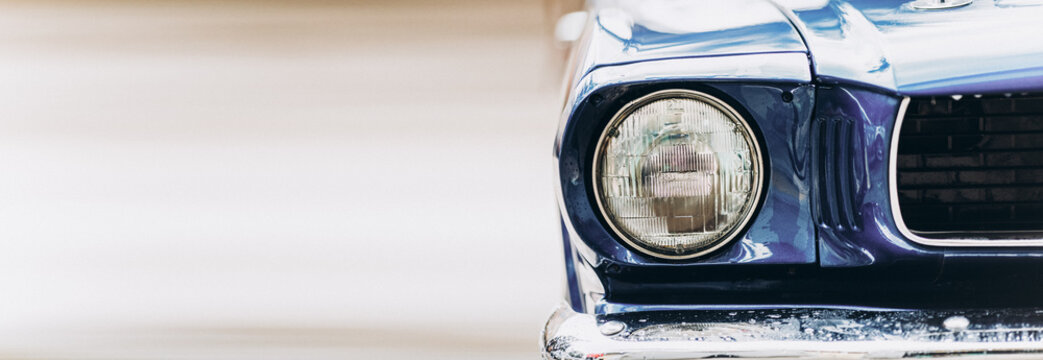 Wide closeup headlights of retro muscle car. Car exterior detail