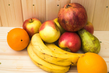 Various fruits apples, bananas, oranges, pomegranates on natural wooden background. Healthy food