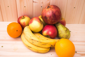 Various fruits apples, bananas, oranges, pomegranates on natural wooden background. Healthy food
