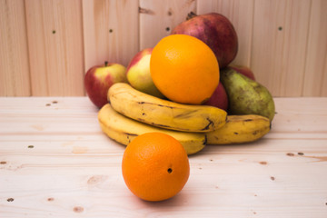 Various fruits apples, bananas, oranges, pomegranates on natural wooden background. Healthy food