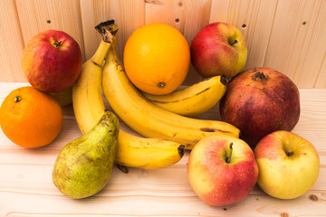 Various fruits apples, bananas, oranges, pomegranates on natural wooden background. Healthy food