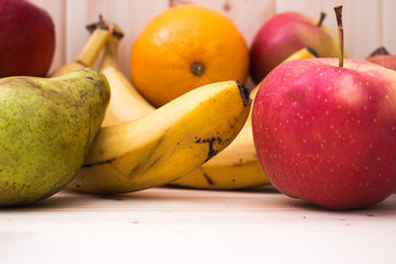 Various fruits apples, bananas, oranges, pomegranates on natural wooden background. Healthy food