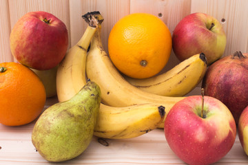 Various fruits apples, bananas, oranges, pomegranates on natural wooden background. Healthy food