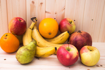 Various fruits apples, bananas, oranges, pomegranates on natural wooden background. Healthy food