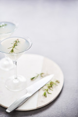 Summer drink. Refreshing summer alcoholic cocktail with rosemary or sparkling gin and lemonade on marble serving plate over dark concrete table. Copy space for text. Selective focus.