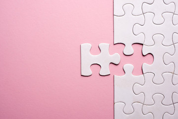 Incomplete white jigsaw puzzle pieces on pink background