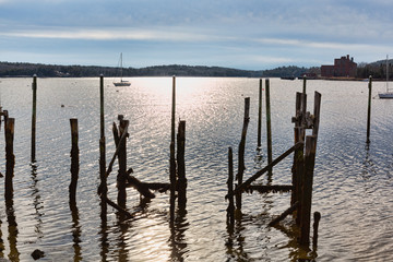 Old wood pilings ruins with a sailboat in the distance