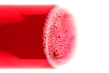 Bubbles on surface of congealed red liquid in a bottle