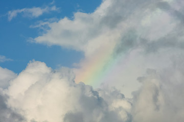 Fototapeta na wymiar Small faint rainbow inside clouds