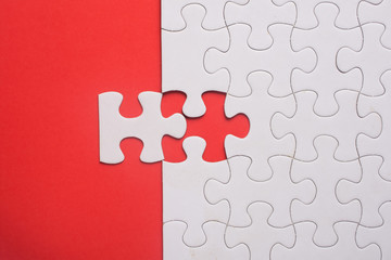 Incomplete white jigsaw puzzle pieces on red background