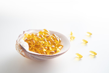 A side view of a handful of transparent yellow-golden tablets lies in a clamshell on a white isolated background.