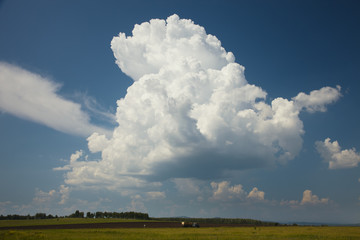 A growing thundercloud on the background of a rural landscape.