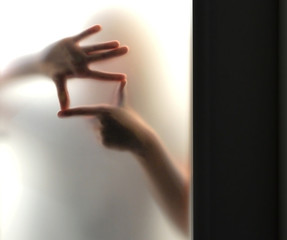 Hands silhouette making frame behind frosted glass
