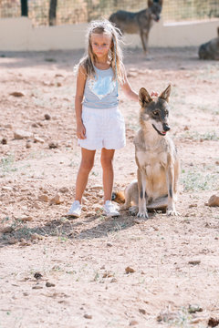 Little blonde girl with wolf in zoo