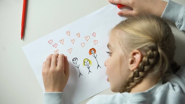 Little girl painting family with heart signs, orphan dreaming about parents