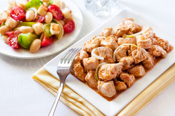 Turkey stew in tomato mustard sauce with onion on square plate