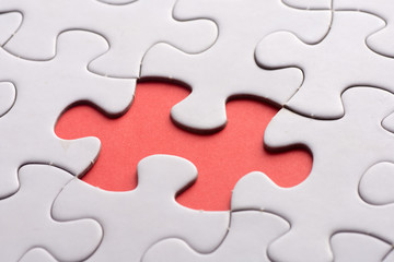 Fototapeta premium Unfinished white jigsaw puzzle pieces on red background