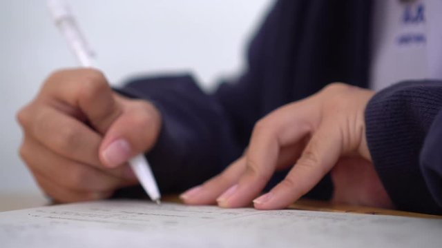 School / university Students hands taking exams, writing examination room with holding pencil on optical form answers paper sheet on desk doing final test in classroom. Education assessment Concept