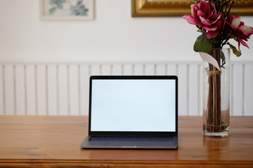 Mockup laptop computer and rose flower on wooden office desk.