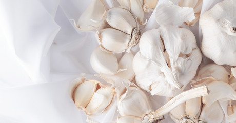 Bulbs and garlic cloves on white textile.