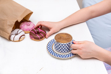 Cup of coffee with milk, donuts, women's hands,
