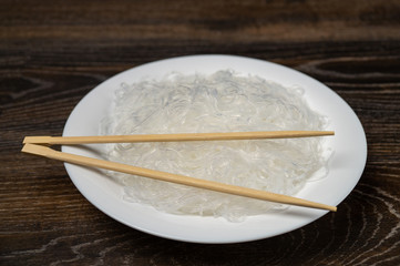 Rise noodles in black bowl on wooden background