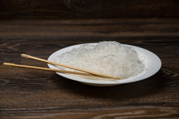 Rise noodles in black bowl on wooden background