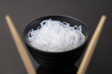Rise noodles in black bowl on wooden background