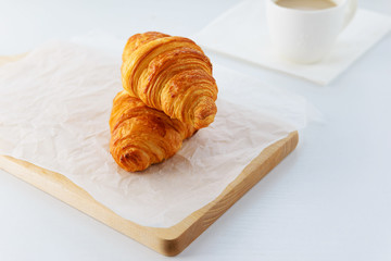 Croissants with a cup of coffee on a wooden board