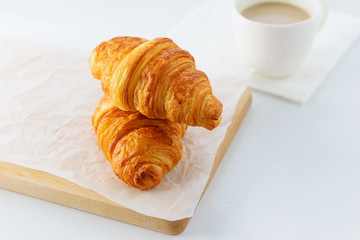 Croissants with a cup of coffee on a white table