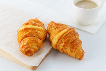 Croissants with a cup of coffee on a wooden board