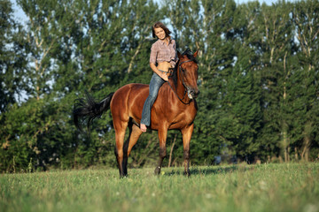 Beautiful cowgirl bareback ride her horse in woods glade at sunset