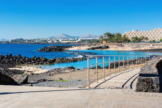 Lagoon with turquoise clear water in Playa Jablillo beach, in Costa Teguise, Lanzarote, Canary islands. Sandy beach with blue sea, volcanic rocks