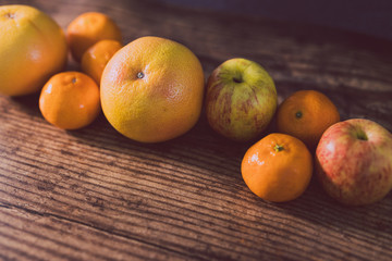 healthy fruit including oranges grapefruit and apples on dark wooden surface with copyspace