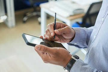 Close-up image of businessman using stylus when working on smartphone